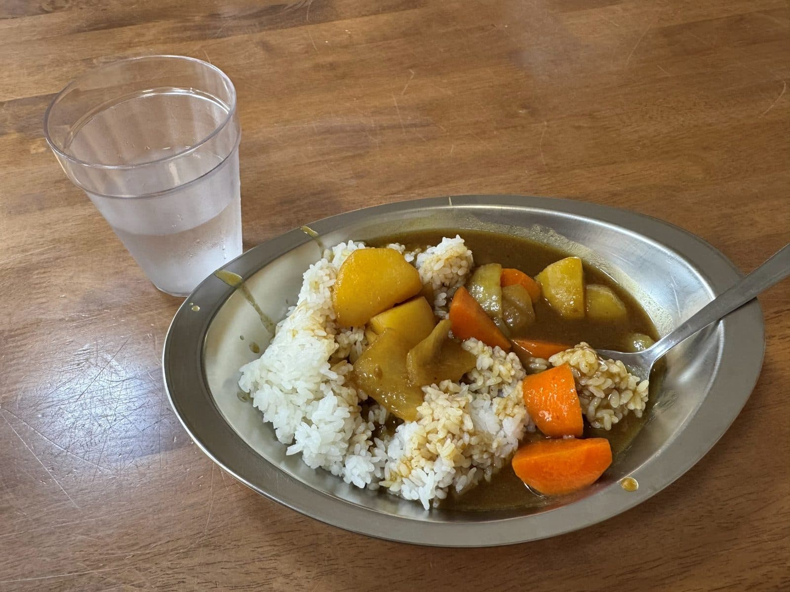 行程午餐的咖哩飯,裝在鐵盤裡,旁邊是一杯水